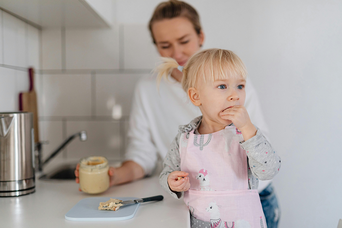 niña comiendo en la cocina con su madre